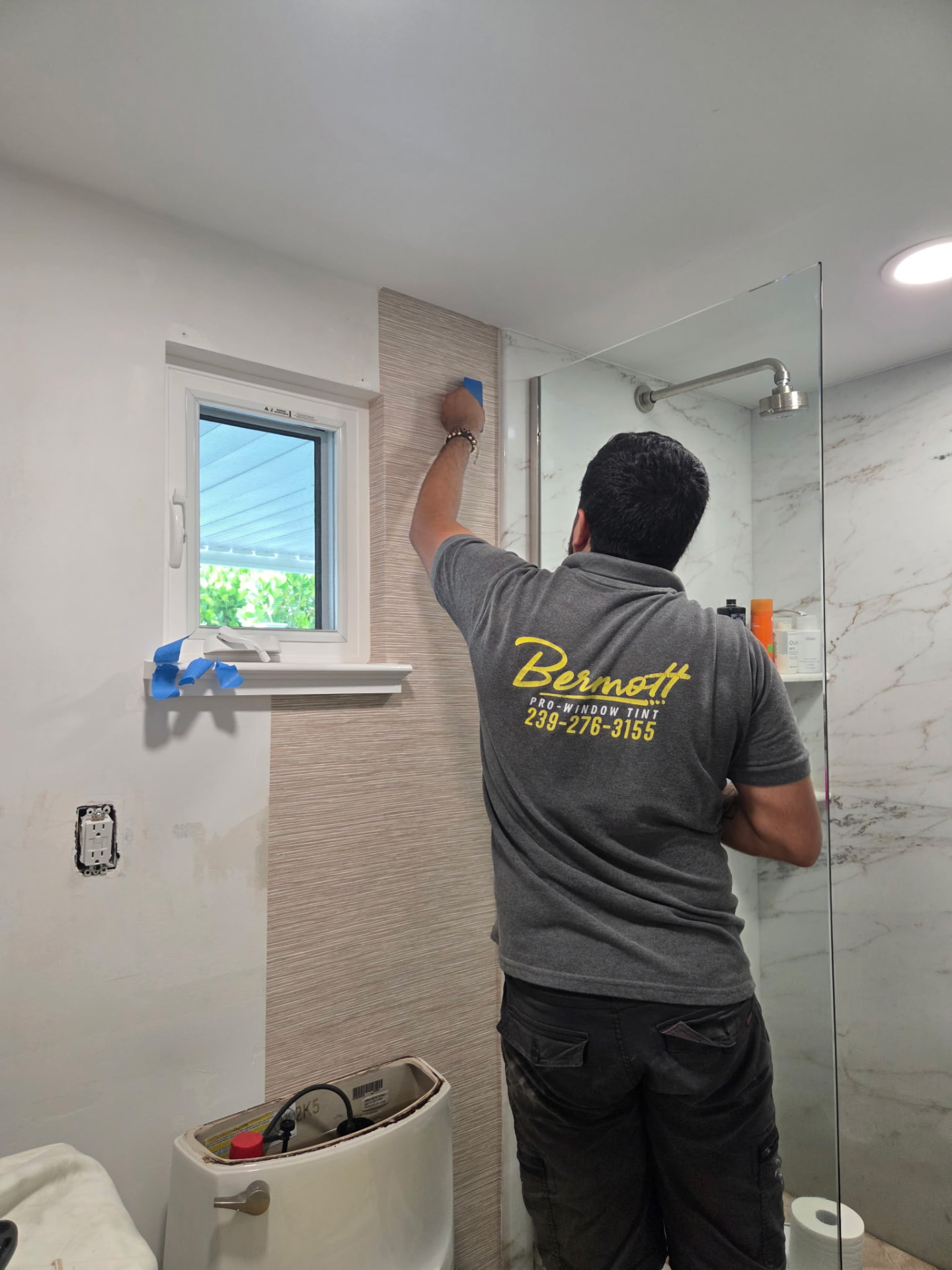 Bermott installer smoothing textured wallpaper in a bathroom