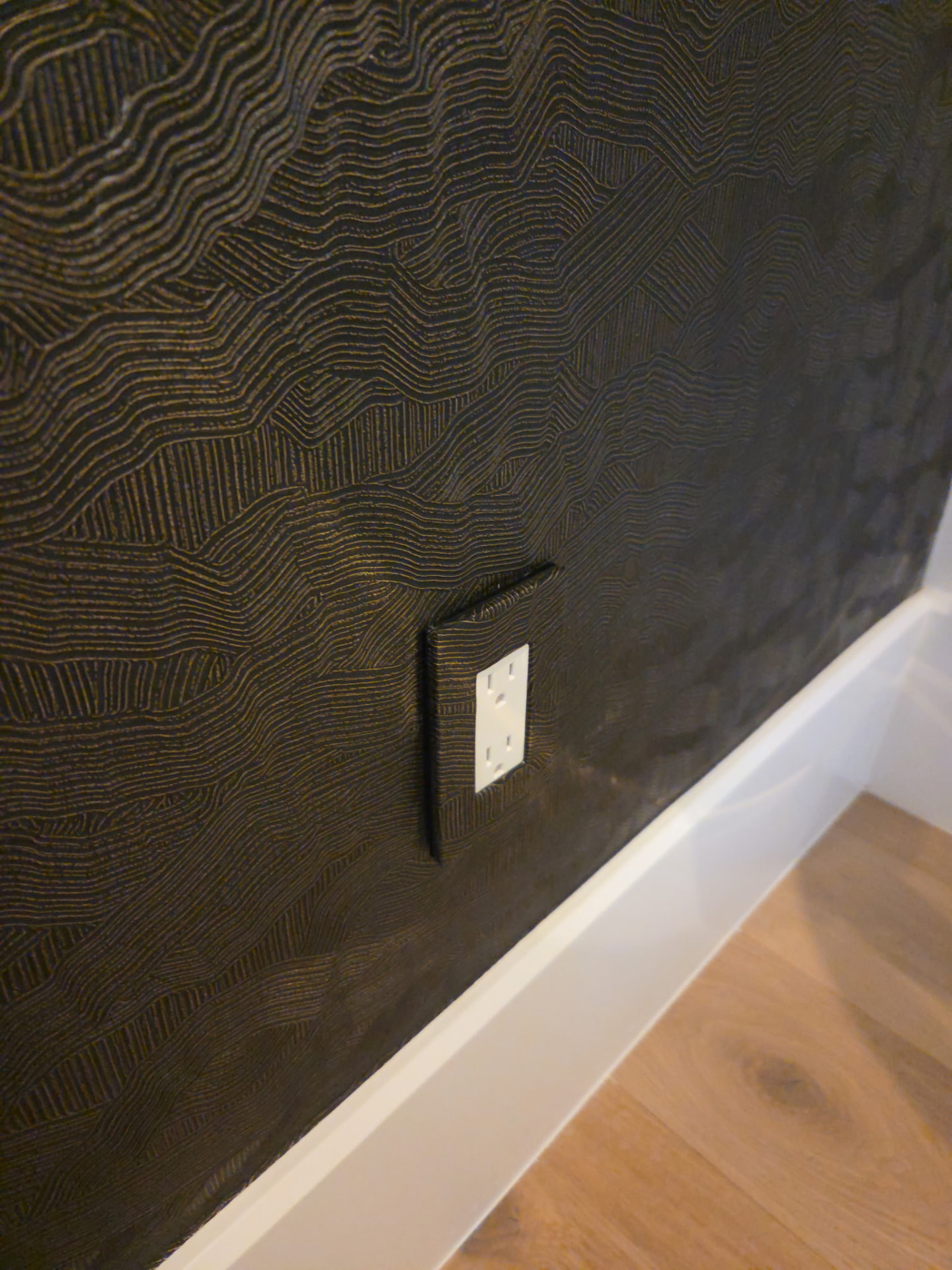 Dark textured wallpaper with a neatly matched outlet cover